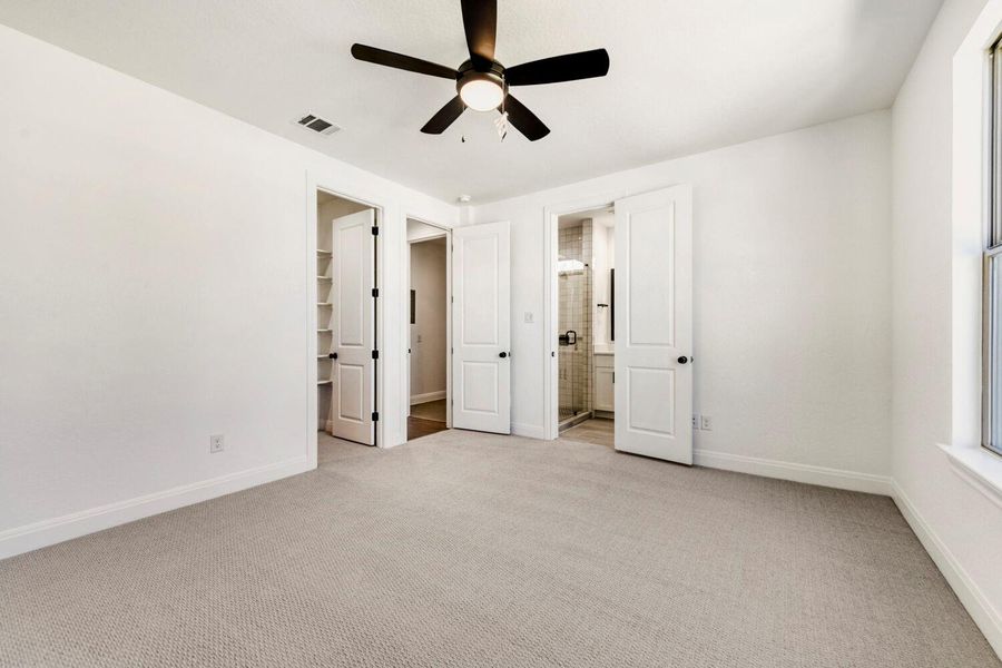Unfurnished bedroom with a spacious closet, light colored carpet, ceiling fan, and ensuite bathroom Unfurnished bedroom with a spacious closet, light colored carpet, ceiling fan, and ensuite bathroom