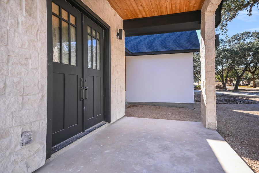 View of exterior entry featuring a shingled roof, covered porch, and stucco siding