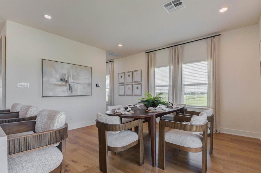 The dining area is bright, open, and thoughtfully designed for both casual meals and entertaining. Surrounded by large windows dressed with soft drapery, this space is filled with natural light and offers peaceful outdoor views. The open-concept layout allows for easy flow into the kitchen and living areas, creating a welcoming environment perfect for hosting or everyday dining. The picture shown is from the model home with the same floor plan, Rev floor plan.