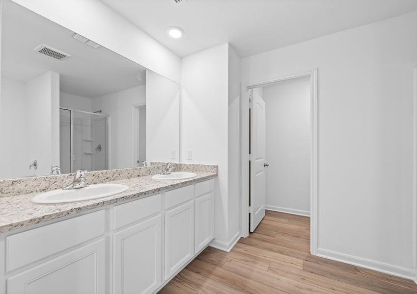 Master bathroom with a two-sink vanity, walk-in shower, and soaking tub.