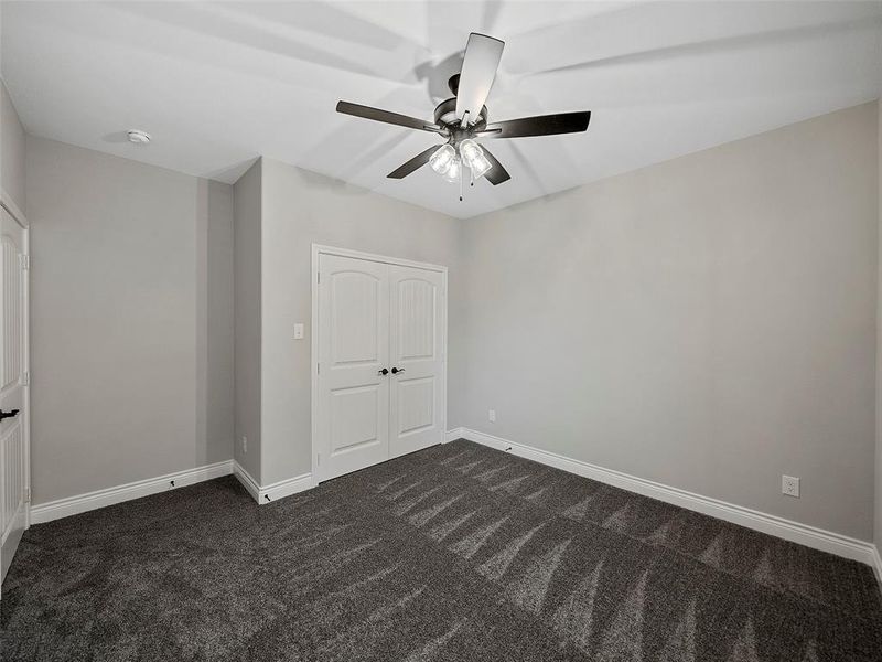 Unfurnished bedroom with dark colored carpet, a closet, and ceiling fan Unfurnished bedroom with dark colored carpet, a closet, and ceiling fan