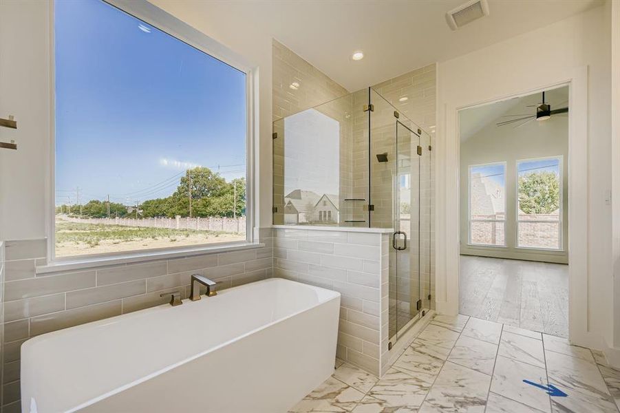 Bathroom featuring marble look tiles, a freestanding bath, a shower stall, recessed lighting, and ceiling fan Bathroom featuring marble look tiles, a freestanding bath, a shower stall, recessed lighting, and ceiling fan