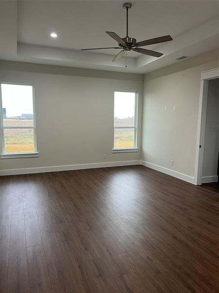 Master bedroom with a tray ceiling, ceiling fan, and dark hardwood / wood-style floors