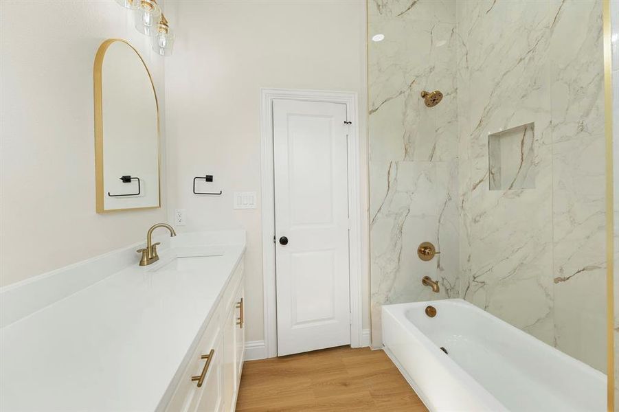 Bathroom with vanity, washtub / shower combination, and light wood-type flooring