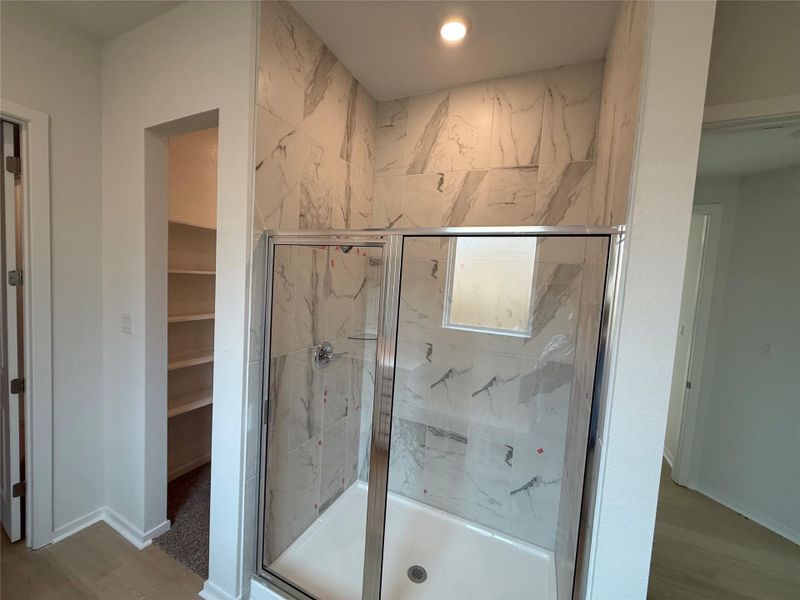 Bathroom featuring a marble finish shower, wood finished floors, and a spacious closet Bathroom featuring a marble finish shower, wood finished floors, and a spacious closet