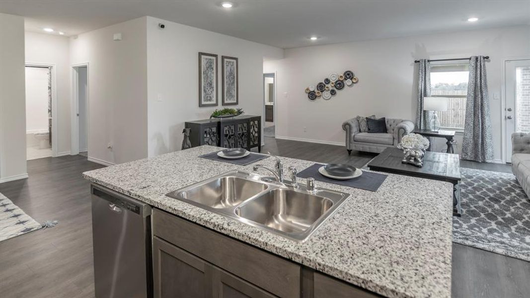 Kitchen featuring open floor plan, dark wood-style floors, stainless steel dishwasher, a center island with sink, and recessed lighting