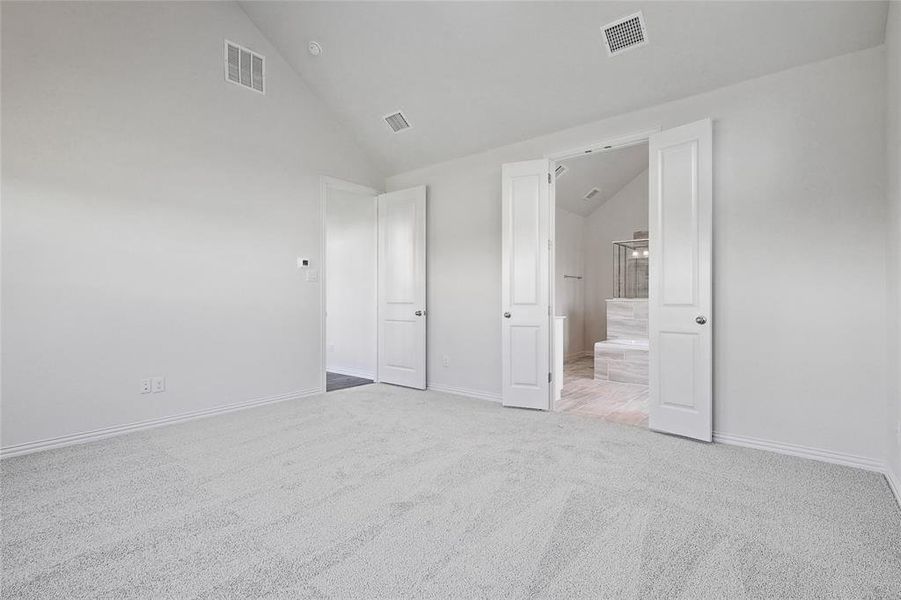 Unfurnished bedroom with high vaulted ceiling and carpet flooring