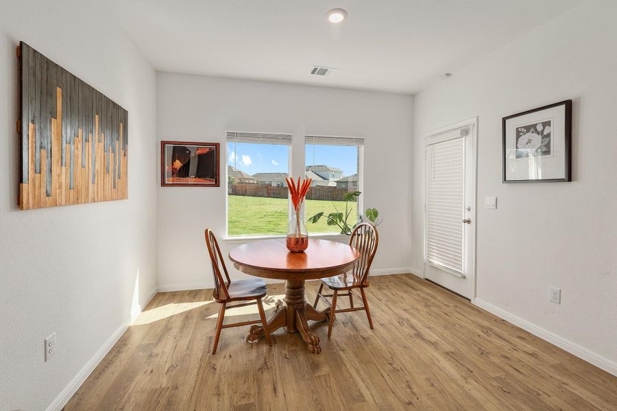 Dining area featuring wood-finish flooring, two large windows, a white door with integrated blinds, and recessed lighting Dining area featuring wood-finish flooring, two large windows, a white door with integrated blinds, and recessed lighting