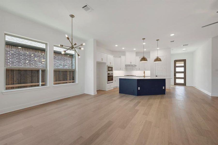 Kitchen with open floor plan, a chandelier, a kitchen island with sink, light countertops, and two tone color scheme