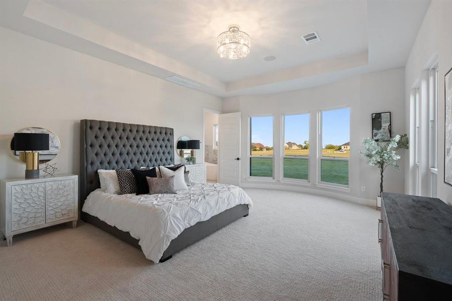 Carpeted bedroom featuring a notable chandelier and a raised ceiling