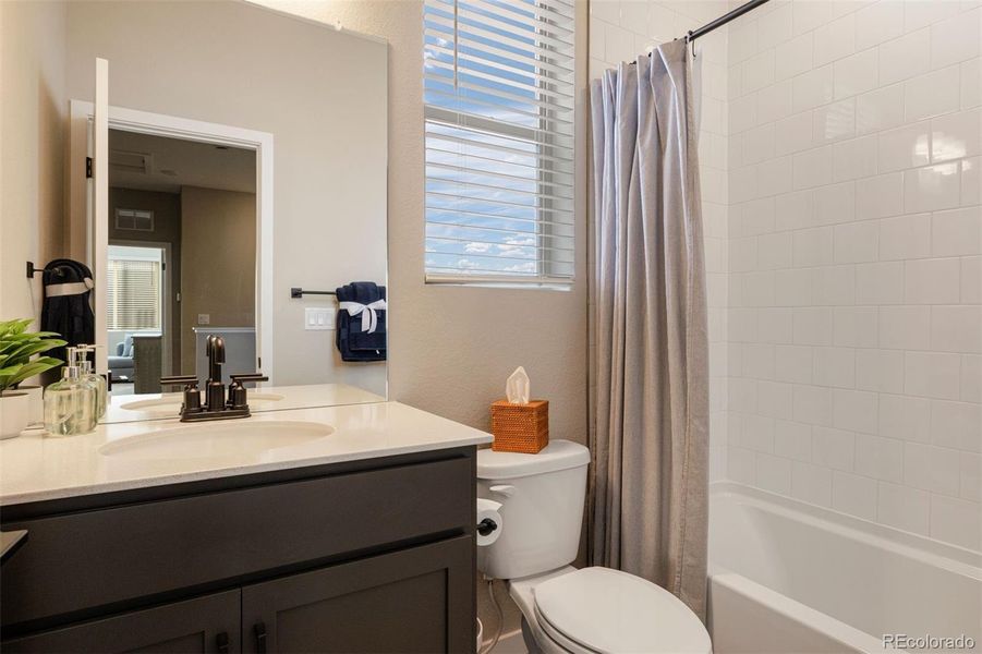 Full bathroom located on the upper level with a single vanity, warm cabinets and a shower/tub combination with subway tile surround.