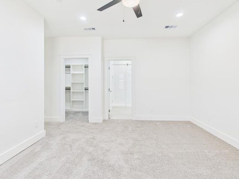 Unfurnished bedroom with a walk in closet, light colored carpet, a ceiling fan, ensuite bath, and recessed lighting Unfurnished bedroom with a walk in closet, light colored carpet, a ceiling fan, ensuite bath, and recessed lighting