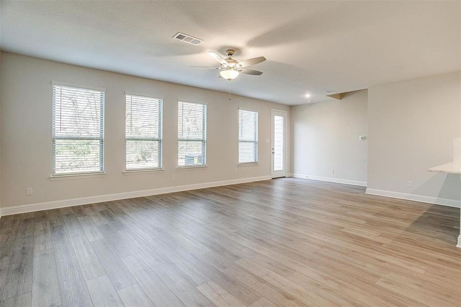 Unfurnished living room featuring a ceiling fan, plenty of natural light, visible vents, and light wood-style floors