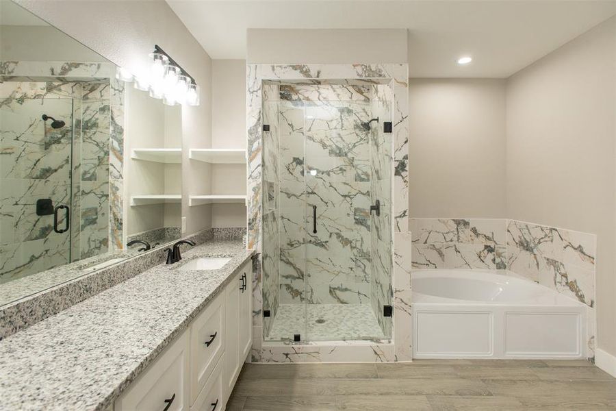 Bathroom featuring shower with separate bathtub, double vanity, and hardwood / wood-style flooring