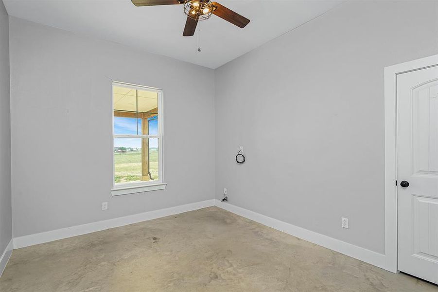 Unfurnished room featuring concrete floors, a ceiling fan, and baseboards