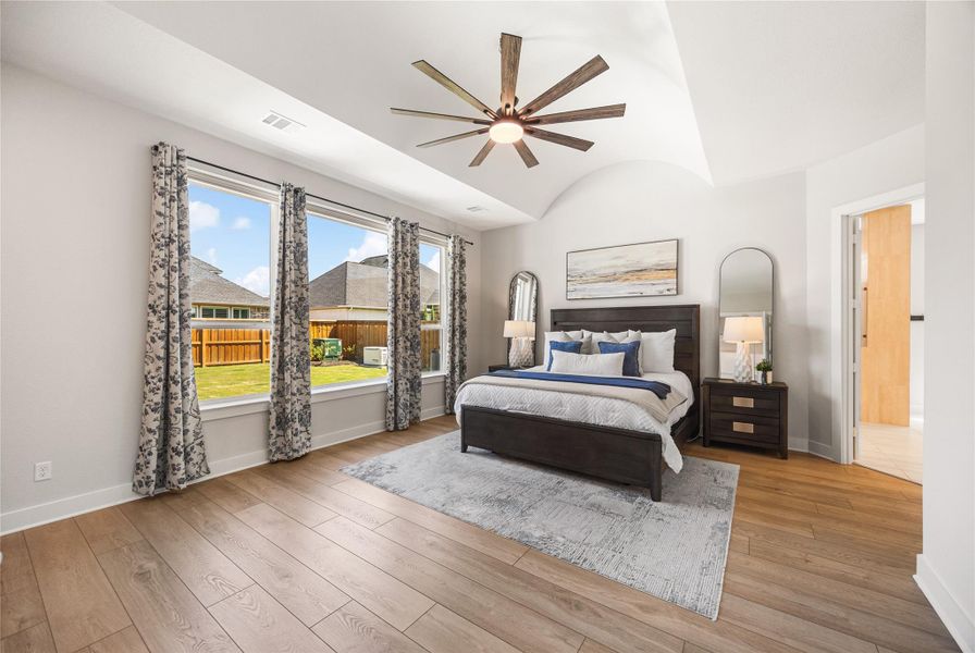 The spacious primary suite offers a peaceful retreat with oversized proportions, abundant natural light, and beautiful views of the backyard oasis.