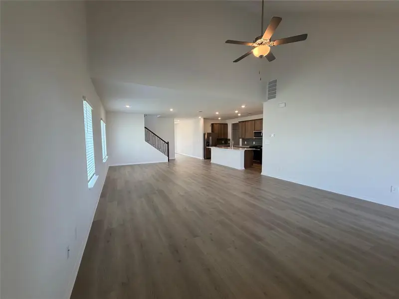 Unfurnished living room with dark wood finished floors, a towering ceiling, a ceiling fan, recessed lighting, and stairs