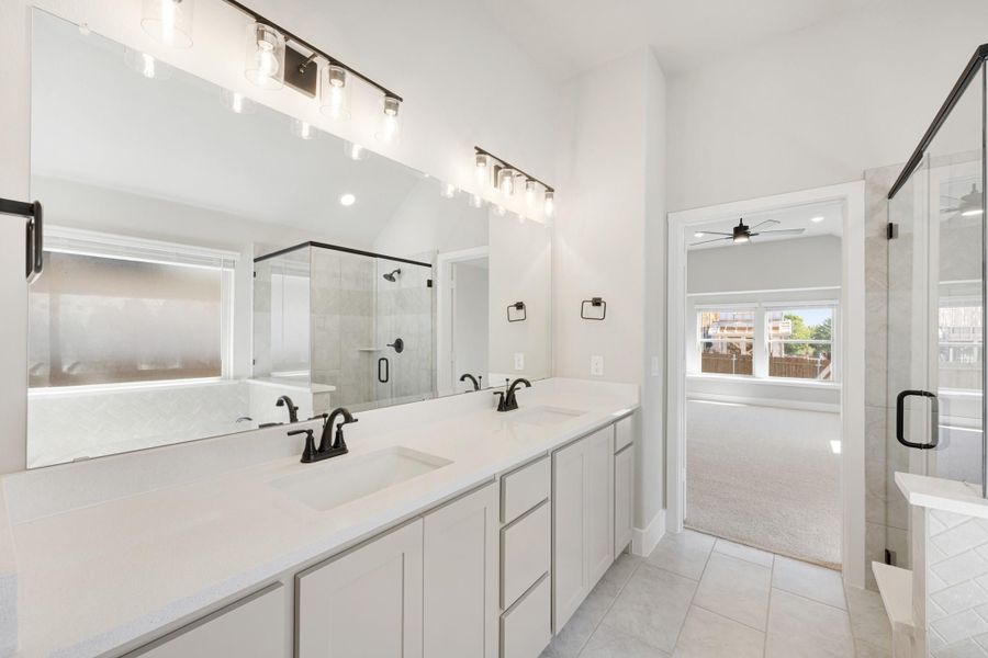 Master bathroom with double vanity, white quartz countertops, glass shower, and black fixtures