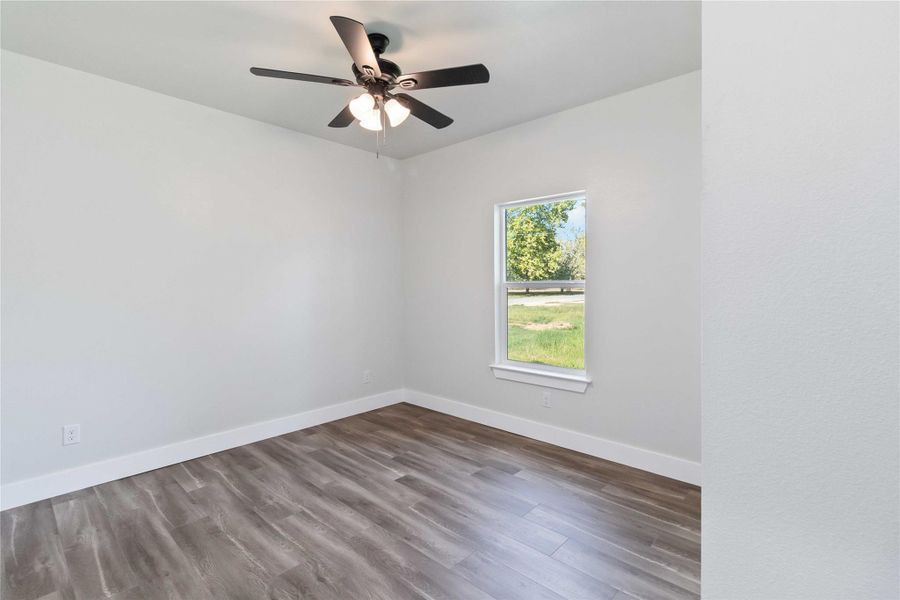Unfurnished room featuring dark wood finished floors and a ceiling fan