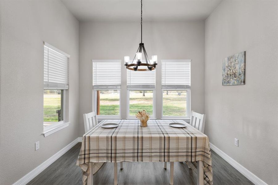 Dining space featuring dark wood-style floors and a chandelier