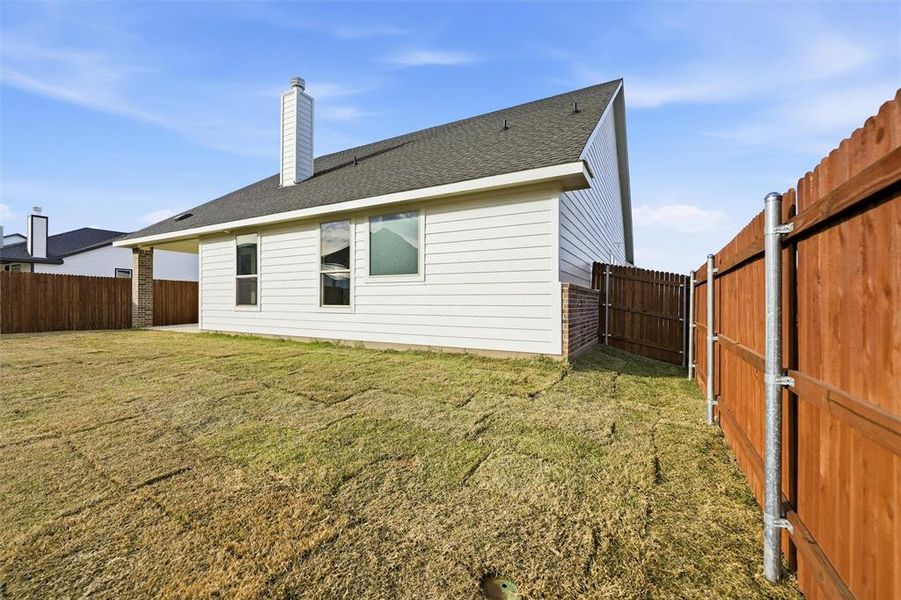 Back of property featuring a chimney, a shingled roof, a fenced backyard, a patio, and brick siding