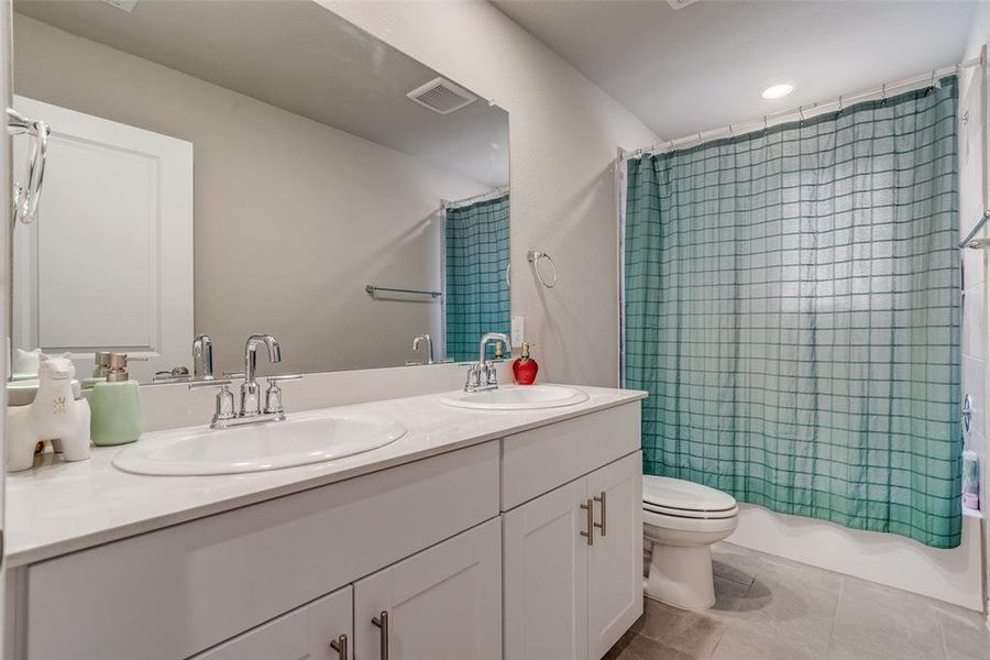 Bathroom featuring shower / bathtub combination with curtain, double vanity, light tile patterned floors, and recessed lighting Bathroom featuring shower / bathtub combination with curtain, double vanity, light tile patterned floors, and recessed lighting
