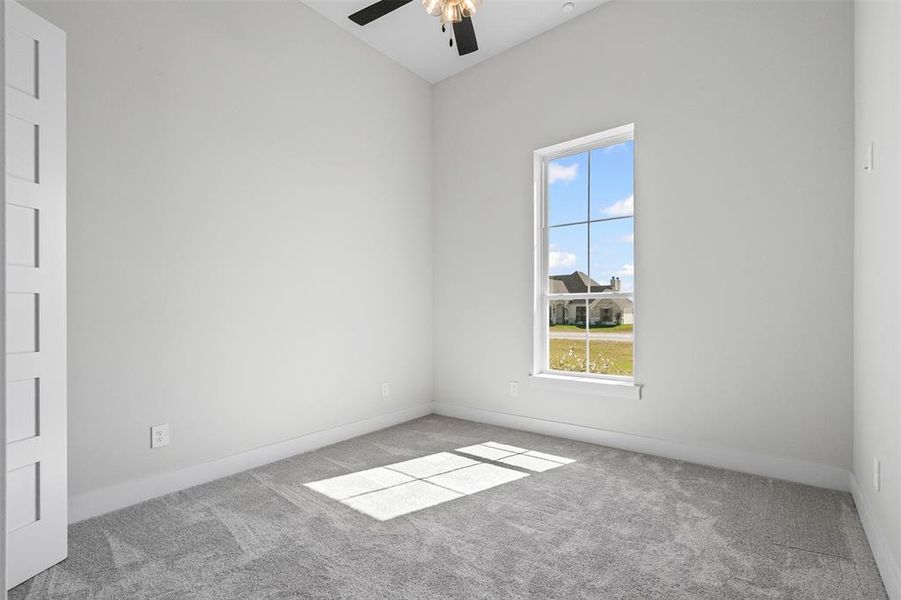 Carpeted empty room featuring baseboards and ceiling fan
