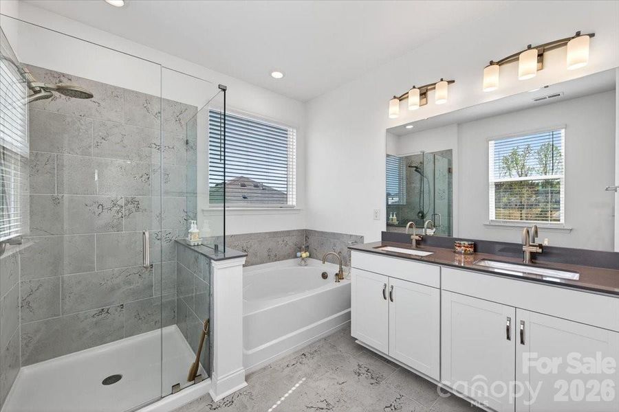 Large primary bath with tiled floors and quartz countertop dual vanity.