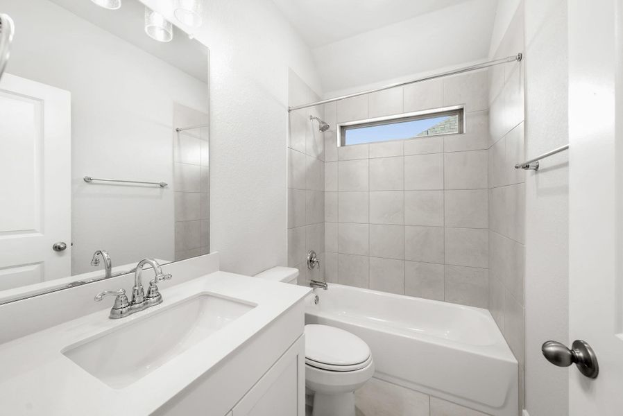 A well-appointed bathroom features a pristine vanity, a bright mirror, and a tiled shower-bath combination.