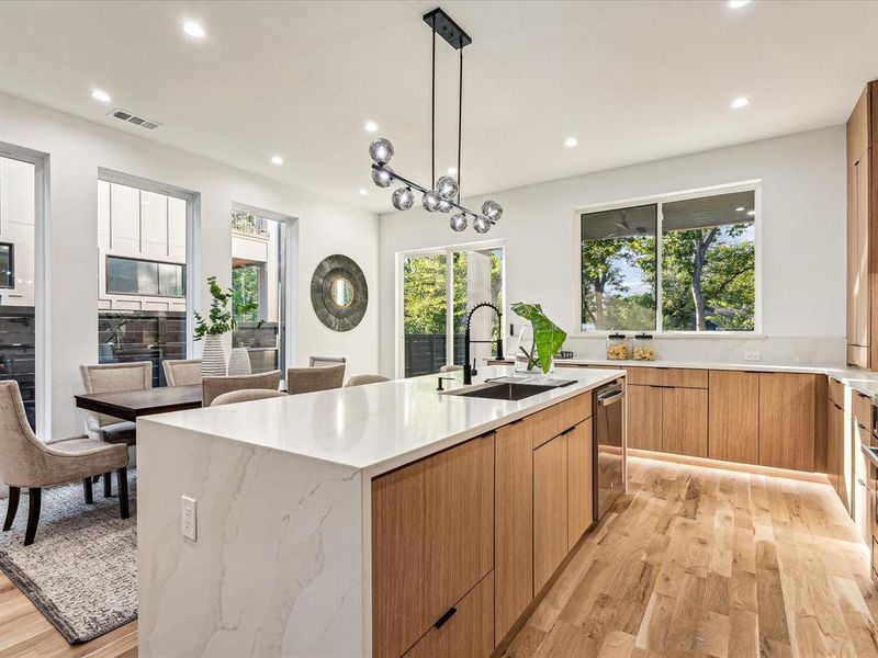 Kitchen featuring pendant lighting, sink, a large island, light hardwood / wood-style flooring, and a notable chandelier