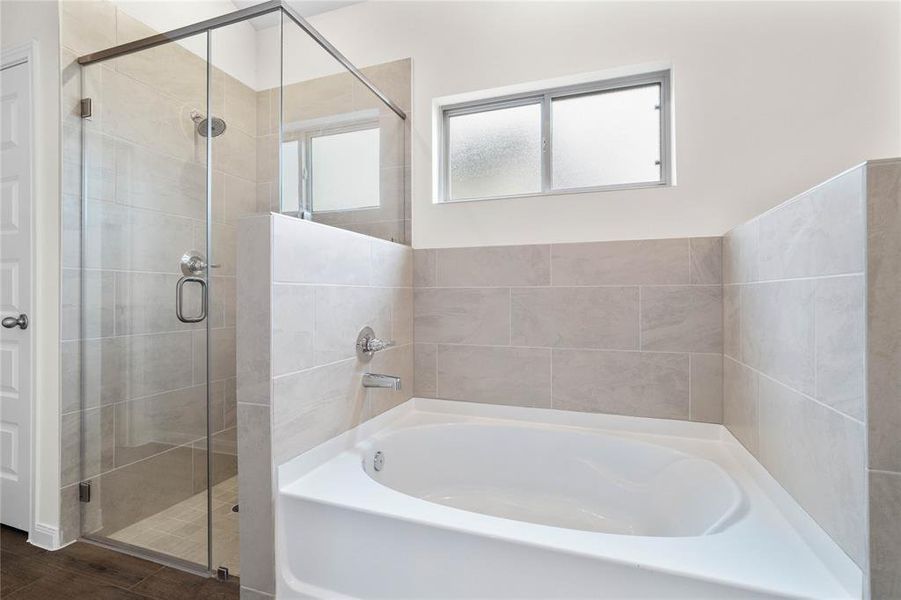 Additional view of the primary bathroom features a walk-in shower with tile surround, separate garden tub for soaking after a long day with custom tile detailing, high ceilings, neutral paint, sleek and modern finishes.