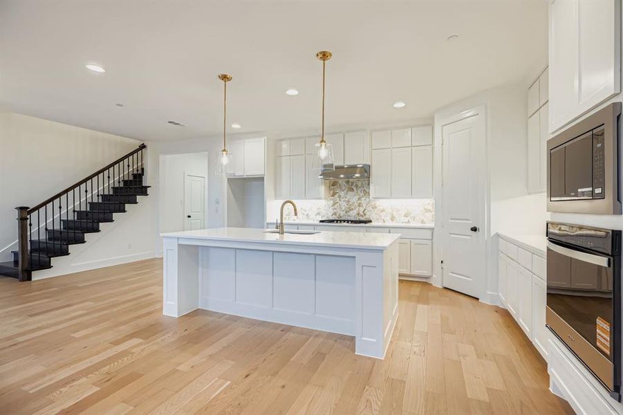 Kitchen featuring decorative backsplash, hanging light fixtures, a kitchen island with sink, white cabinetry, and recessed lighting Kitchen featuring decorative backsplash, hanging light fixtures, a kitchen island with sink, white cabinetry, and recessed lighting