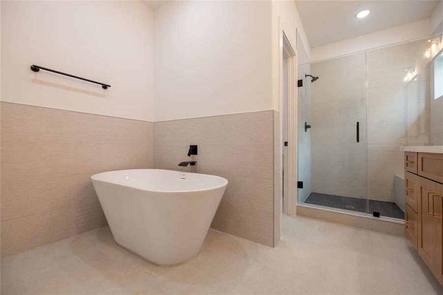 Primary bathroom boasts his and hers vanities, a private water closet, a glass-enclosed walk in shower, with an incredible soaking tub.