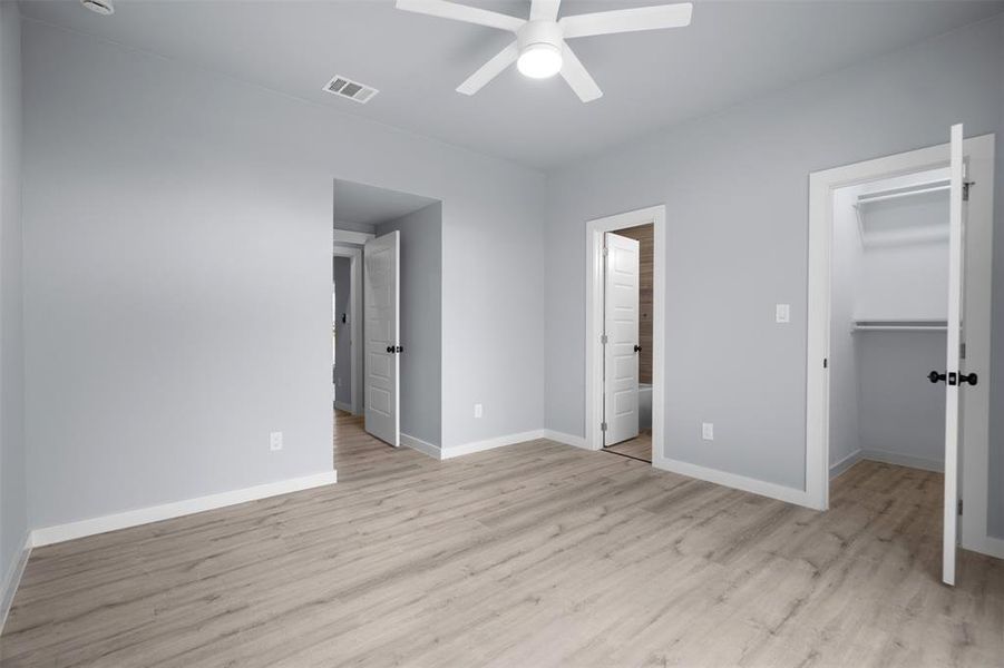 Unfurnished bedroom featuring a walk in closet, light wood-type flooring, and a ceiling fan Unfurnished bedroom featuring a walk in closet, light wood-type flooring, and a ceiling fan