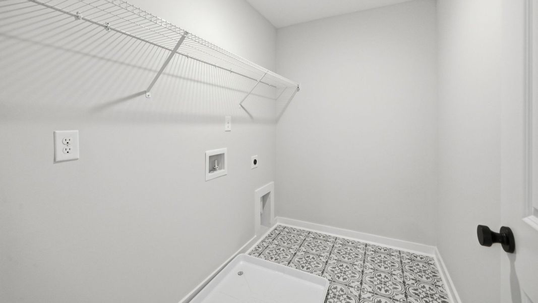 Dedicated laundry space with accent tile flooring and ventilated shelf