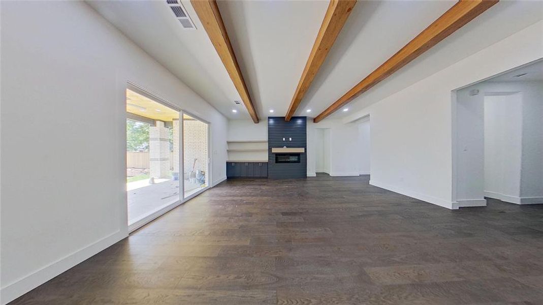 Unfurnished living room featuring beamed ceiling, dark wood-style flooring, recessed lighting, and a fireplace