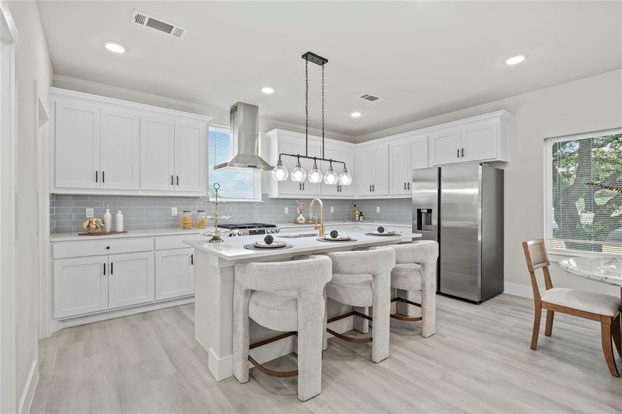 Kitchen with stainless steel fridge, a kitchen bar, tasteful backsplash, white cabinets, and light wood-style flooring Kitchen with stainless steel fridge, a kitchen bar, tasteful backsplash, white cabinets, and light wood-style flooring