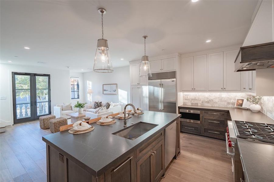 Kitchen with appliances with stainless steel finishes, white cabinetry, sink, a kitchen island with sink, and dark brown cabinetry