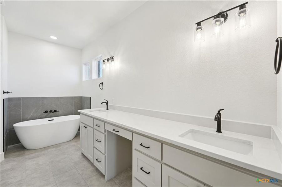Dual vanities and a freestanding soaking tub define this pristine bathroom oasis. Dual vanities and a freestanding soaking tub define this pristine bathroom oasis.
