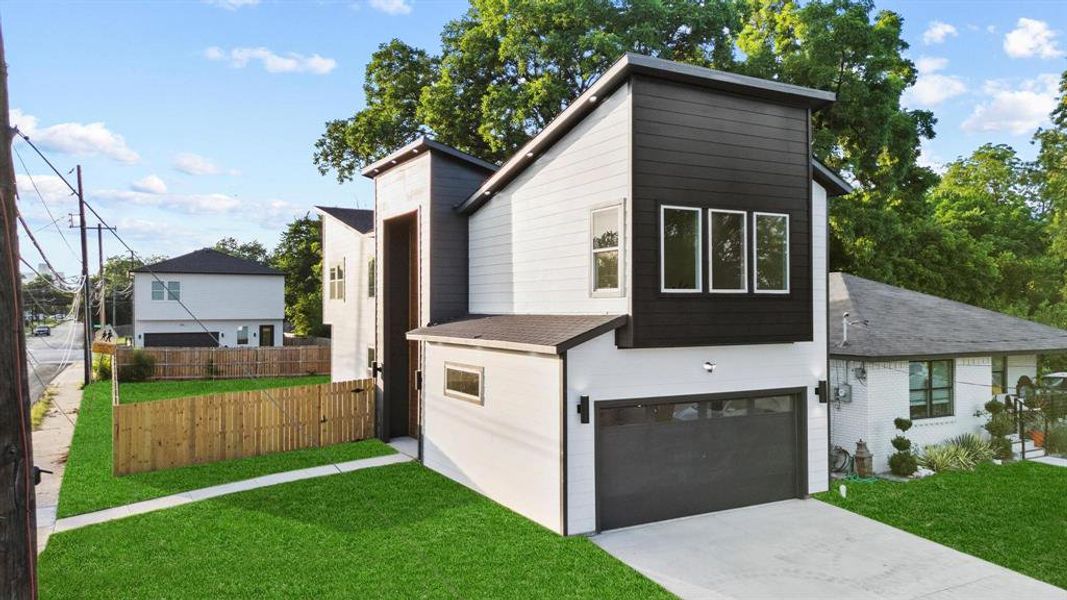 View of property exterior featuring a garage, a shingled roof, and driveway