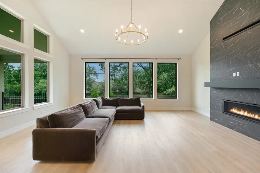 Natural light floods this living room with a striking floor-to-ceiling fireplace and wide plank flooring.