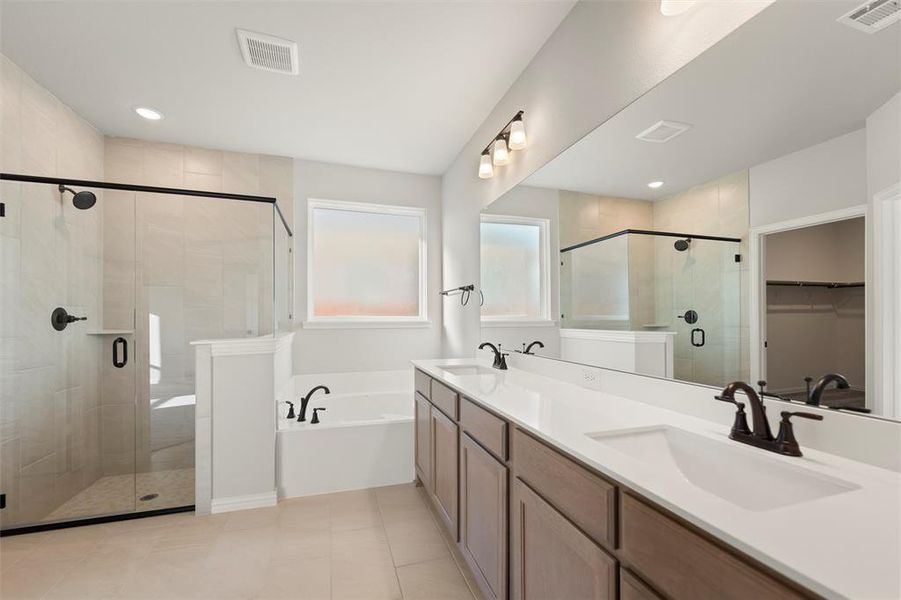 Full bath with a spacious closet, double vanity, a shower stall, a garden tub, and light tile patterned flooring Full bath with a spacious closet, double vanity, a shower stall, a garden tub, and light tile patterned flooring