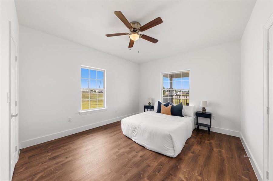 Bright room featuring wood-finish flooring, white walls, and a ceiling fan with integrated lighting