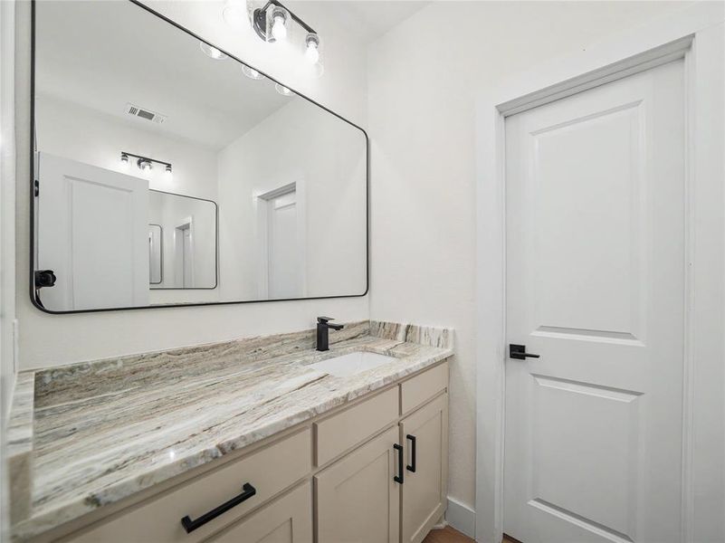 Bathroom vanity featuring a light-toned countertop, an undermount sink, and matte black fixtures Bathroom vanity featuring a light-toned countertop, an undermount sink, and matte black fixtures