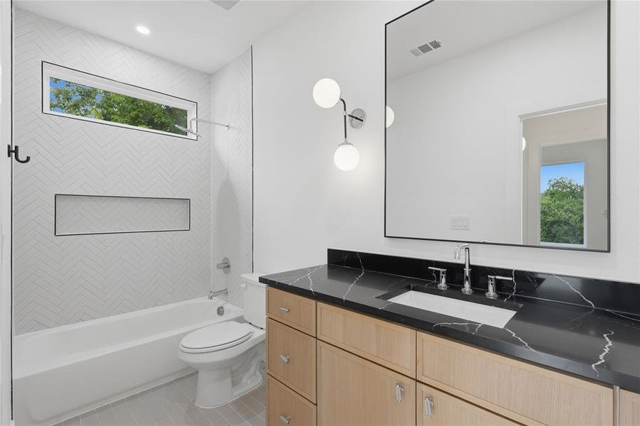 Bathroom featuring a light wood-finish vanity with a dark stone-look countertop and an integrated rectangular sink Bathroom featuring a light wood-finish vanity with a dark stone-look countertop and an integrated rectangular sink
