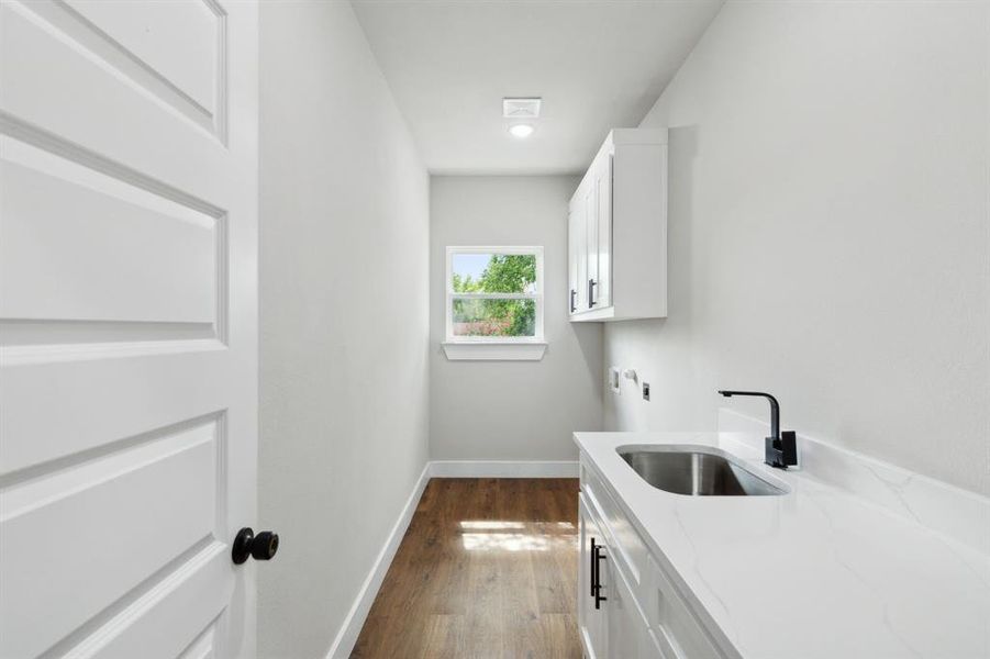 Clothes washing area featuring washer hookup, dark wood-type flooring, cabinets, and sink