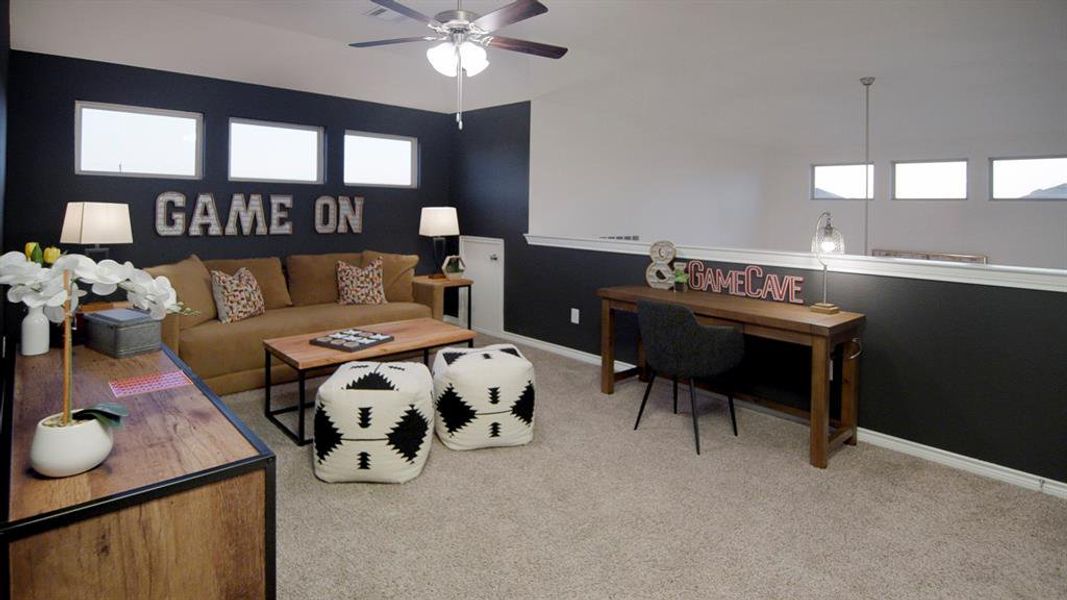 Spacious loft area featuring carpet flooring, a ceiling fan with integrated lighting, and a half-wall partition Spacious loft area featuring carpet flooring, a ceiling fan with integrated lighting, and a half-wall partition