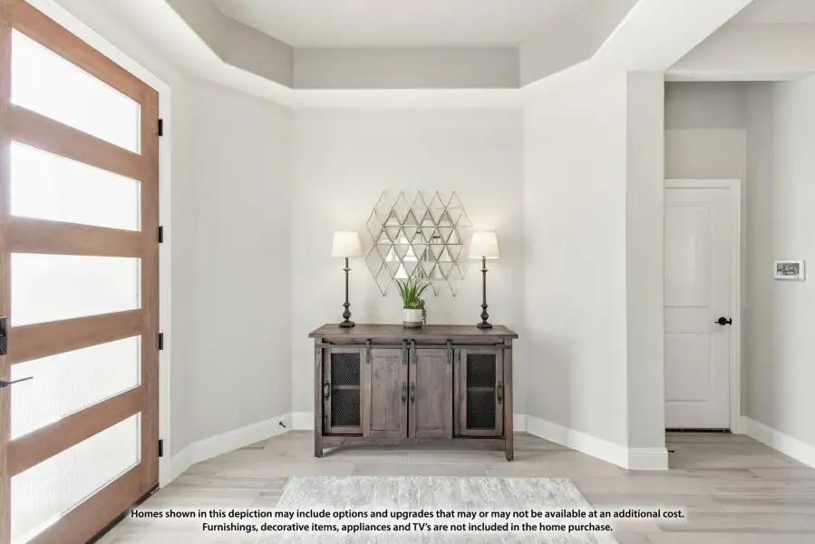 Entryway with wood and glass front door, tray ceiling, and rustic console table with two lamps