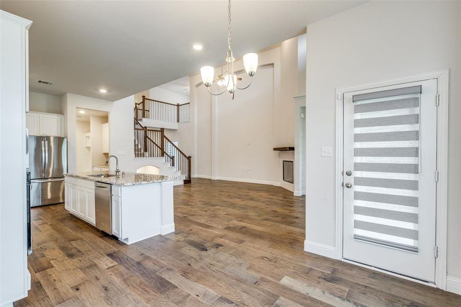 Kitchen featuring a sink, appliances with stainless steel finishes, white cabinets, dark wood finished floors, and light stone countertops