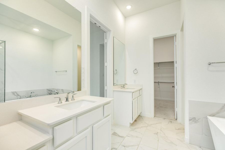 Primary bath featuring a double vanity with a dedicated makeup area, spacious walk-in closet, and stylish recessed lighting.